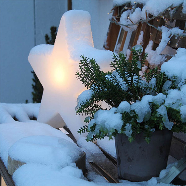 Weatherproof outdoor Christmas light in star shape on a snowy garden terrace