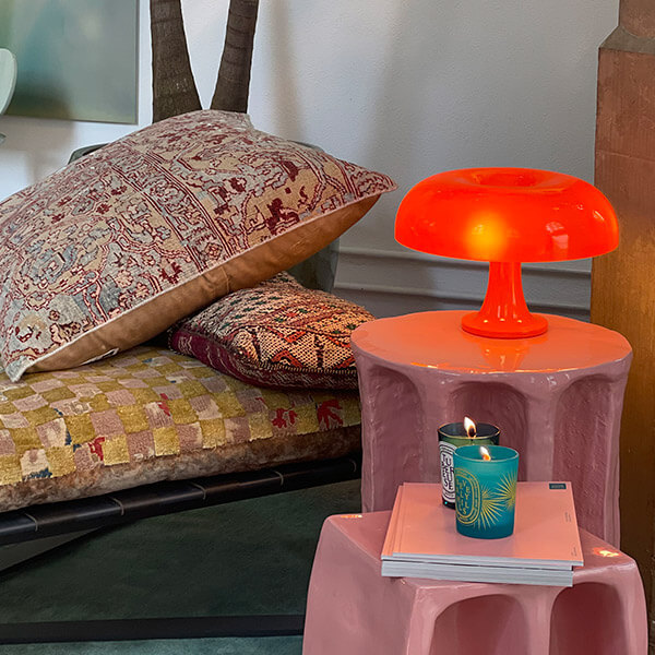 Artemide Nessino orange table lamp on a pink side table in a bedroom